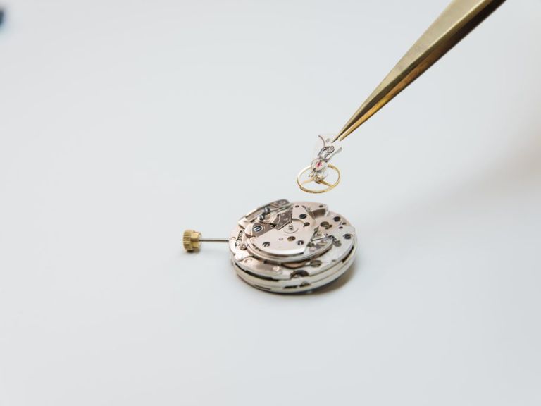Calibre de reloj desmontado y pinzas de relojero